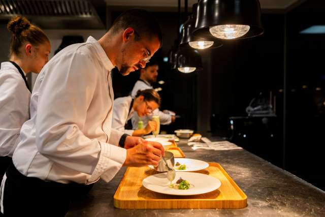 Un chef en cuisine, dressant un plat avec précision sous un éclairage contrôlé.