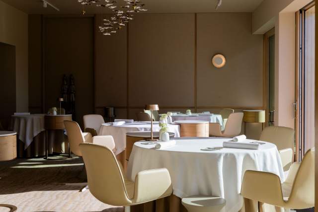 Une salle de restaurant chaleureuse et accueillante, avec des tables rondes élégamment dressées.