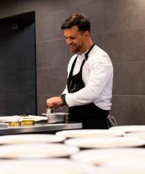 Chef en cuisine concentré sur le dressage soigné d'un plat.