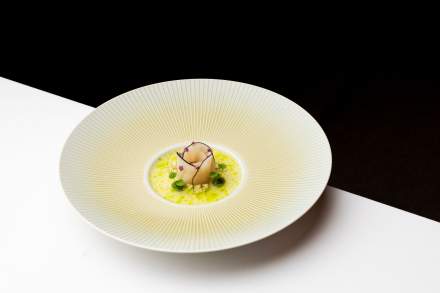 Plat gastronomique raffiné présenté dans une assiette creuse au design épuré.