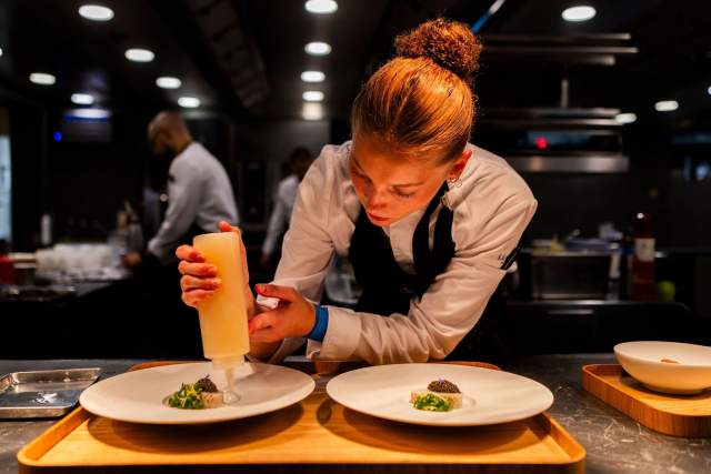 Un membre de l'équipe de cuisine apporte la touche finale à la présentation d'un plat.