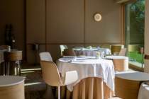 Table de restaurant élégamment dressée avec nappe blanche dans une salle moderne et chaleureuse aux tons beiges.