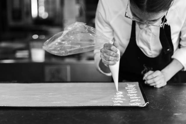 Un geste précis en cuisine pour un dressage soigné d'une préparation.
